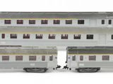 six silver train cars are lined up on a white surface