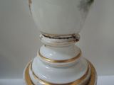 a white vase with gold trim on a white table