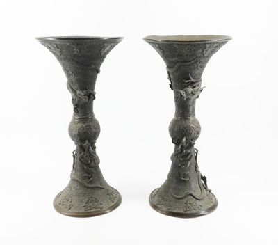 two metal vases sitting next to each other on a white surface