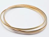 deux bracelets « bang bang » en or posés sur une surface blanche