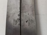 pair of large metal knives sitting on top of a white surface