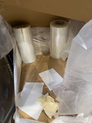 de nombreux rouleaux de film alimentaire posés par terre à côté d'un micro-ondes