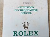 booklet of rolex watch on a wooden table with a crown on it