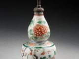 un vase oriental orné d'un oiseau et de fleurs, posé sur un socle
