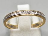 a gold and diamond ring on a white marble stand