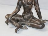 a bronze statue of a woman sitting on the ground