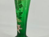 a green vase with flowers on it sitting on a table