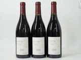 three bottles of red wine are lined up on a white surface