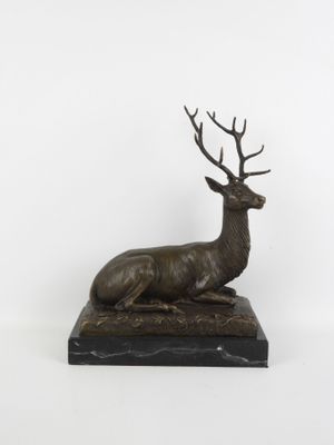 sculpture représentant un cerf assis sur un socle en marbre, sur fond blanc