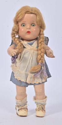 une petite poupée aux cheveux blonds et vêtue d'une robe bleue