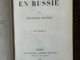 un livre ouvert posé sur une table en bois, à côté d'une pile de livres
