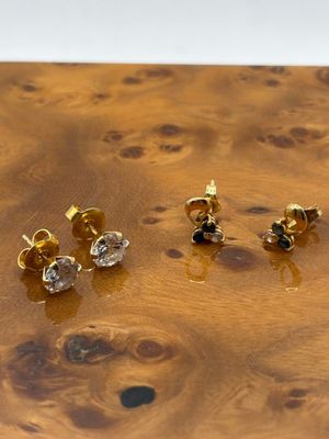 trois paires de boucles d'oreilles en or et diamants posées sur une surface en bois