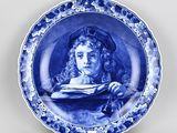 assiette bleue et blanche ornée d'une peinture représentant une femme tenant un livre