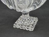 a clear glass bowl with a square base on a table