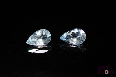 a pair of blue topazte gems on a black surface