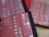 trois classeurs rouges contenant des pièces de monnaie, posés sur une table en bois