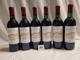 six bottles of wine are lined up on a table
