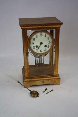une petite horloge en bois avec un pendule posée sur la table