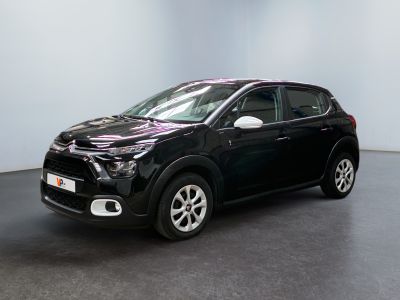 Une voiture noire est garée dans une pièce aux murs blancs.