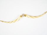 une image représentant un collier en or orné d'un motif incurvé