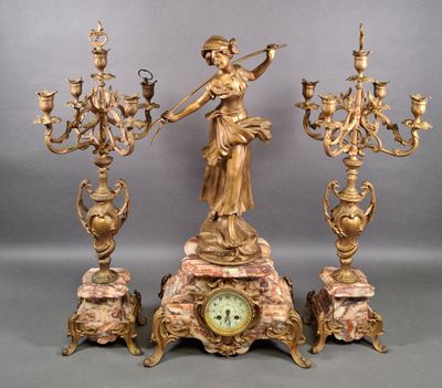 a clock that is sitting on a table with a statue on it