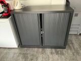 a grey cabinet with two doors open in a kitchen