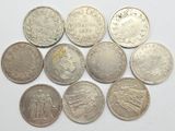 six types différents de pièces d'argent sur une surface blanche