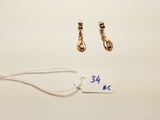 two pairs of gold earrings and a price tag on a white surface