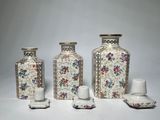 three vases and two cups are sitting next to each other on a white surface
