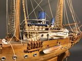 wooden model of a boat with sails and ropes on a wooden stand