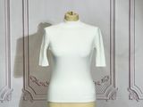 un haut blanc posé sur un mannequin devant un mur