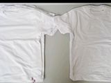 two white t - shirts sitting on top of a table next to each other
