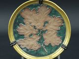 une assiette verte et dorée ornée d'un motif de feuilles