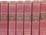 six red books are lined up on a shelf in a row
