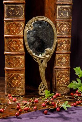 a mirror sitting on top of a table next to a bunch of books