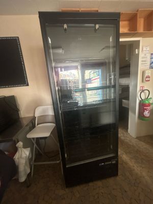 a refrigerator in the middle of a room with a tv on the wall