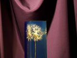 a glass vase with a dandelion in it on a table