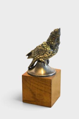 a bronze bird sitting on top of a wooden block