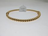 gros plan d'un bracelet en or sur une surface blanche
