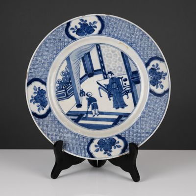 an antique blue and white plate with a picture of a man in a room