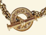 a gold bracelet with a brass clasp and a gun on it