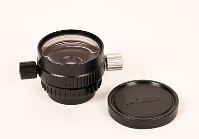 un objectif d'appareil photo et un cache-objectif posés sur une surface blanche