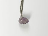 a close up of a necklace with a stone on a chain