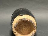 a close up of a black vase on a gray surface