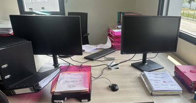 deux écrans d'ordinateur posés sur un bureau devant une fenêtre