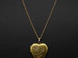 a gold heart locke necklace with a chain on a mannequin mannequin