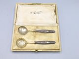 two silver spoons and a spoon in a box on a table