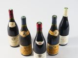 six bottles of wine are lined up in a row on a white surface