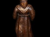 an old wooden statue of a monk holding a rosary on a black background