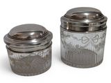 pair of silverplated glass jars with silver lids on a white background